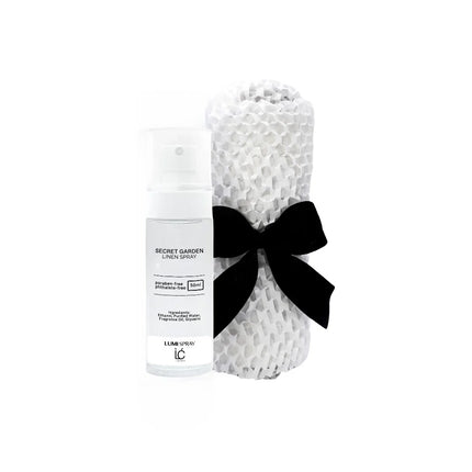 Secret Garden LUMI Room and Linen Spray (50ml) bottle wrapped in a white woven textured cloth tied with a black ribbon bow